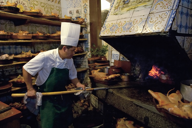 cook putting plate in the oven at Sobrino de Botín